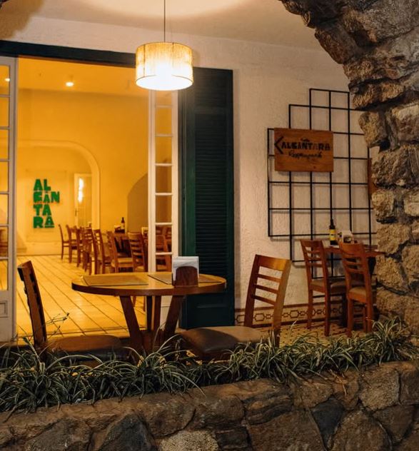 Salão do restaurante Alcântara aberto para a varanda de pedra da pousada