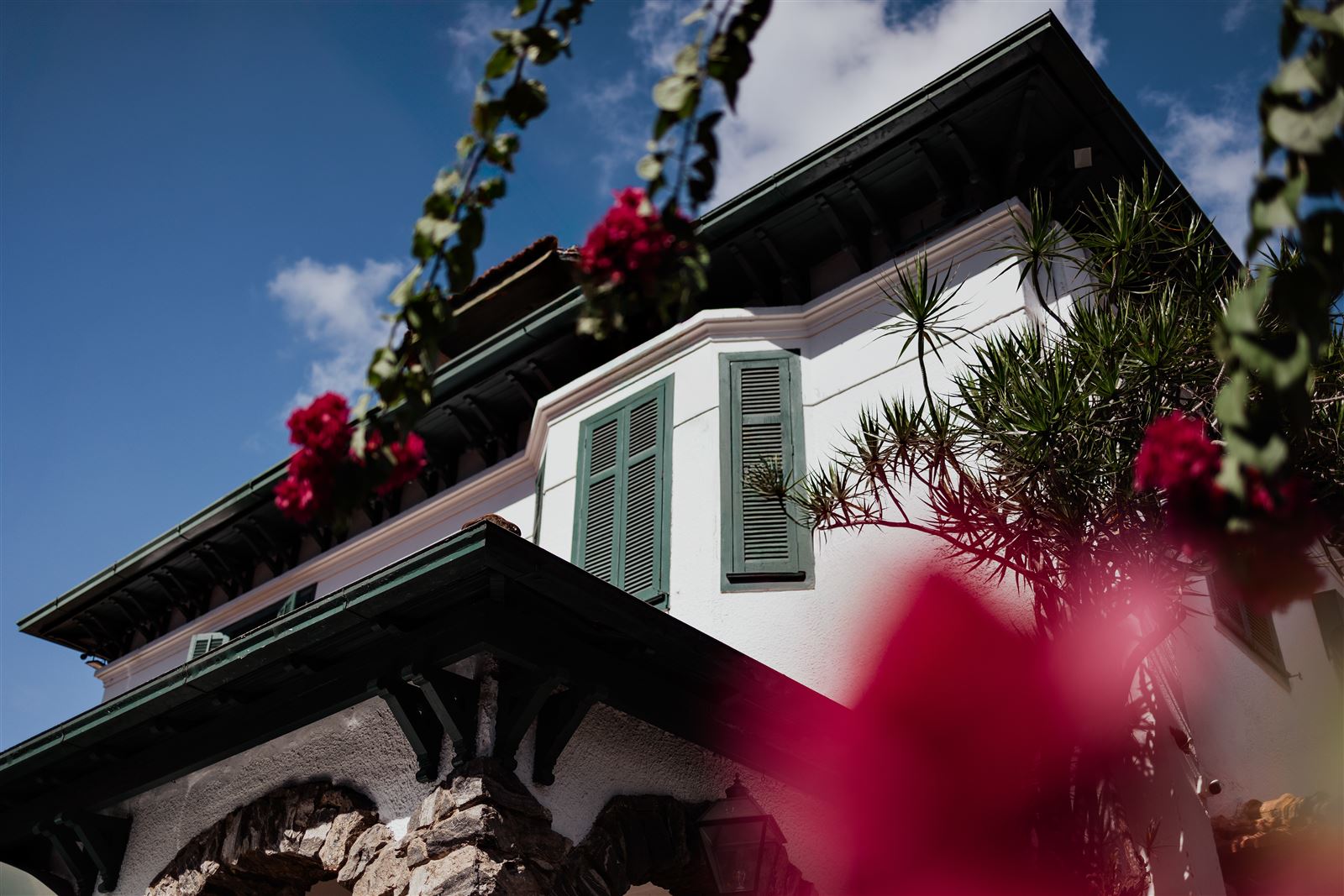 Detalhe da fachada da pousada com flores e janelas verdes