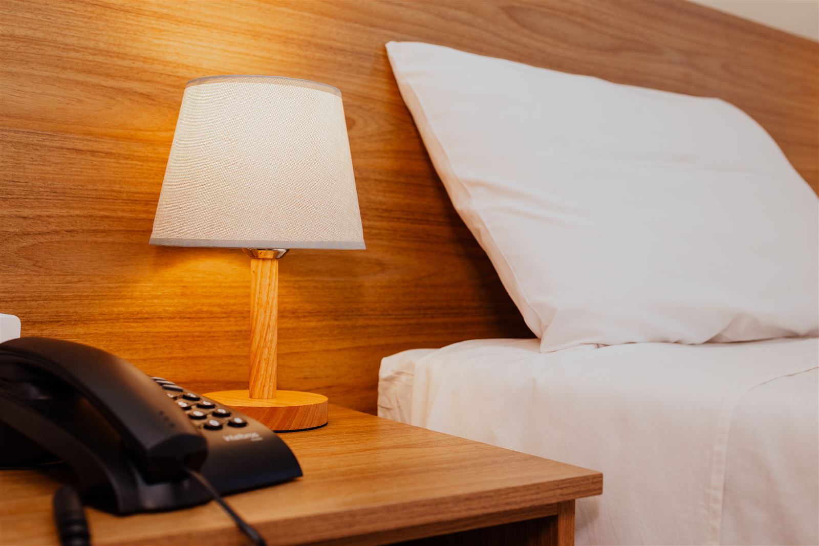 Detalhe do abajur e do telefone ao lado da cama